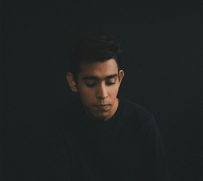 man wearing long sleeved shirt looking down